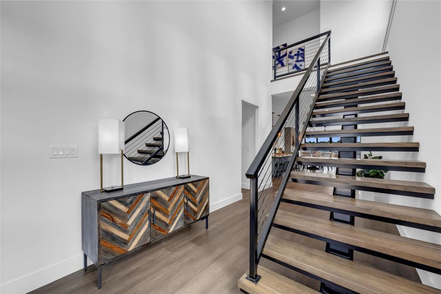 Stairs with a high ceiling and wood finished floors