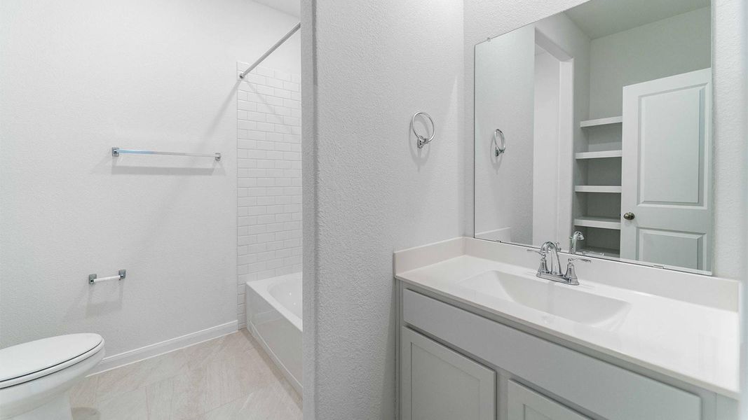 Bathroom with vanity, a textured wall, shower / bath combination, and light tile patterned flooring