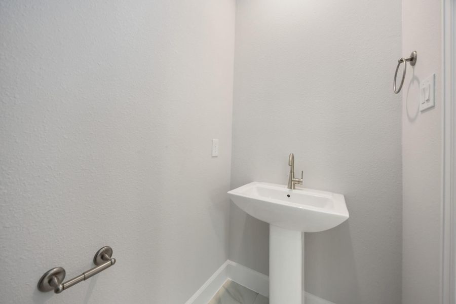 Convenient Style: The downstairs half bath combines practicality with a polished design, featuring a sleek pedestal sink and elegant fixtures, perfect for guests and everyday use. Convenient Style: The downstairs half bath combines practicality with a polished design, featuring a sleek pedestal sink and elegant fixtures, perfect for guests and everyday use.