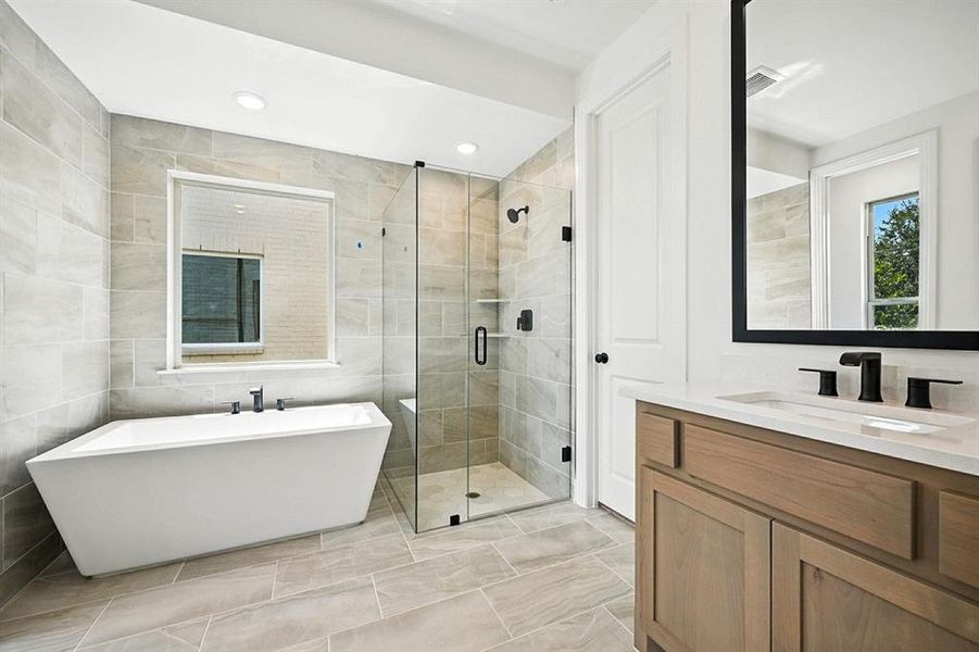 Full bath with tile walls, a stall shower, vanity, a freestanding bath, and recessed lighting Full bath with tile walls, a stall shower, vanity, a freestanding bath, and recessed lighting