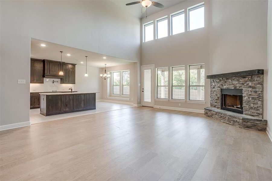 Unfurnished living room with light hardwood / wood-style flooring, a towering ceiling, and plenty of natural light