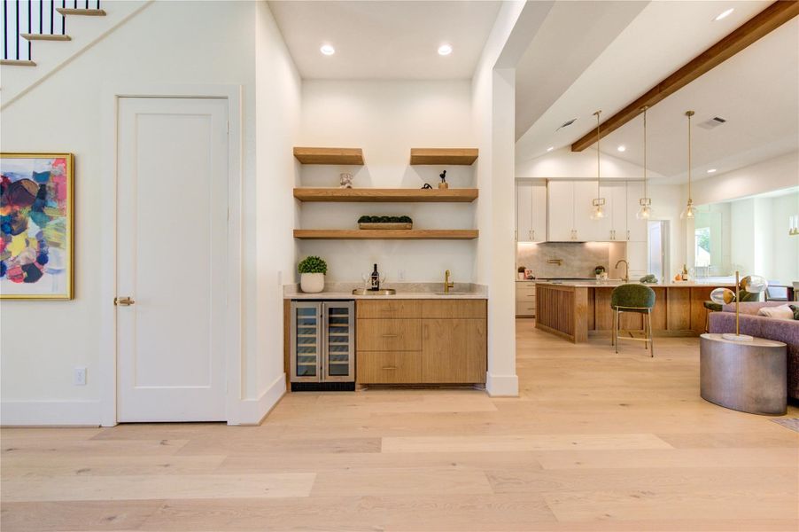 Entertain effortlessly with a beautifully appointed wet bar featuring floating wood shelves, beverage refrigeration, and seamless access to the main living areas.