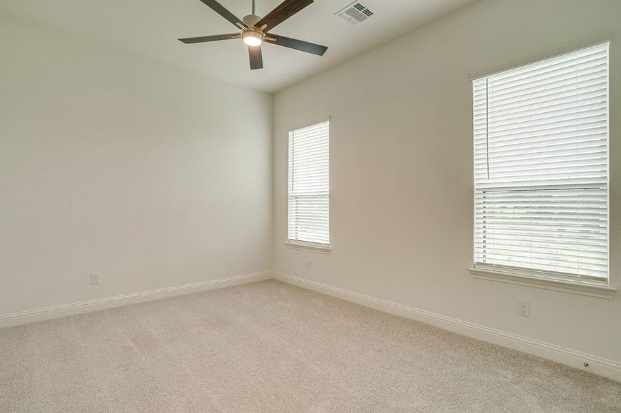Secondary bedroom with ceiling fan and walk in closet