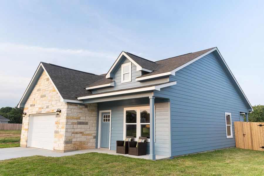 View of front of property with roof with shingles, an attached garage, stone siding, and driveway
