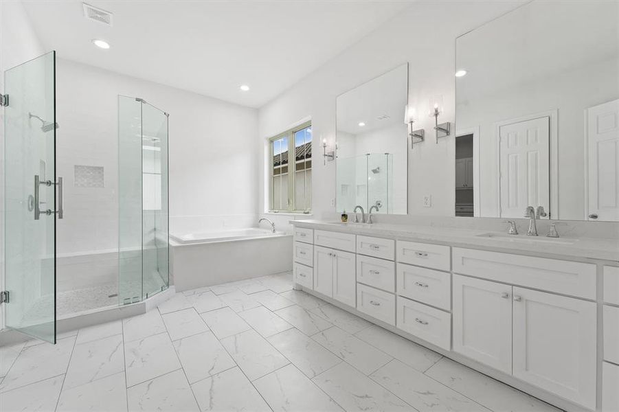 Spacious, modern bathroom featuring a large glass-enclosed shower, a soaking tub, double vanity with ample storage, and sleek white finishes with marble-like tile flooring.