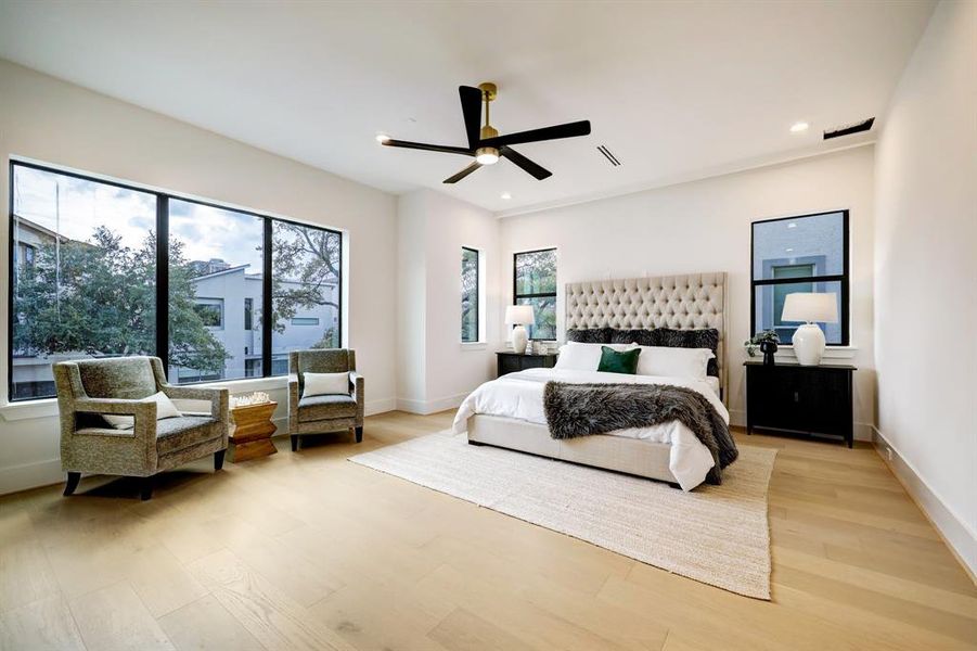 Experience tranquility in the primary bedroom boasting energy-efficient LED ceiling lighting and expansive windows offering serene treetop vistas.