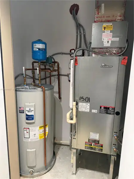 Mechanical utility closet containing a ClimateMaster geothermal heat pump, a Bradford White electric water heater, and a thermal expansion tank with integrated copper piping