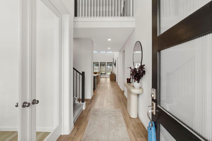 Dramatic grand entry featuring wood-look tile floors and a direct sightline through the open floor plan to the bright living area. Dramatic grand entry featuring wood-look tile floors and a direct sightline through the open floor plan to the bright living area.