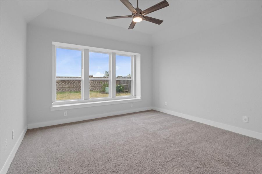 Relax and unwind after a long day in this impressive primary suite! This generously sized room offers plush carpeting, neutral-toned paint, high ceilings with a ceiling fan, and large windows for added comfort and tranquility.