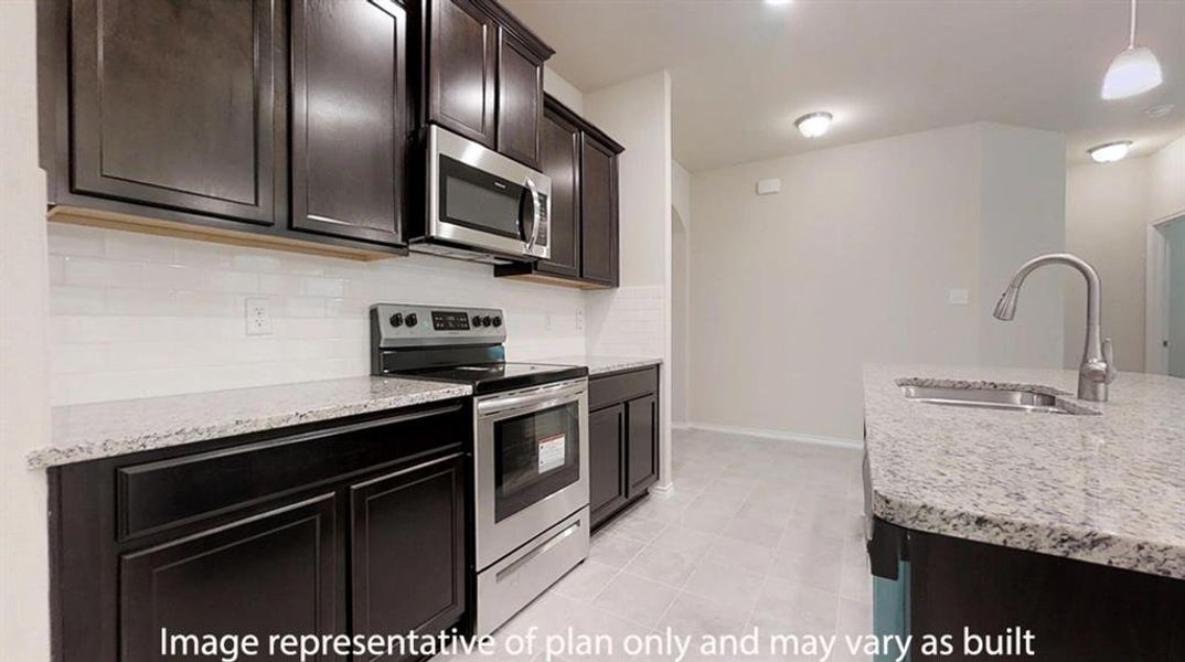 Kitchen with appliances with stainless steel finishes, backsplash, light stone countertops, pendant lighting, and dark brown cabinetry Kitchen with appliances with stainless steel finishes, backsplash, light stone countertops, pendant lighting, and dark brown cabinetry