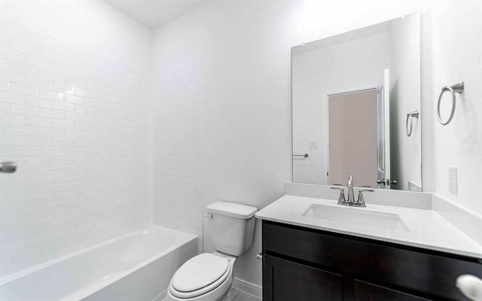Bathroom with white subway tile shower surround, dark wood-finish vanity, light countertop, and chrome fixtures