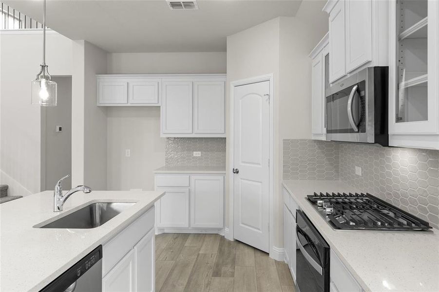 Kitchen with light hardwood / wood-style floors, stainless steel appliances, backsplash, sink, and white cabinetry