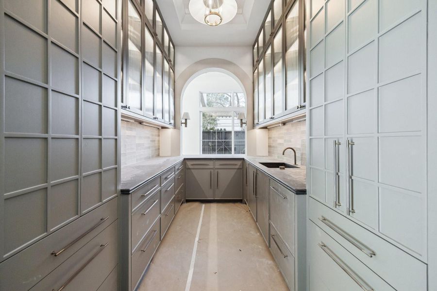 There is a back kitchen/bar/butler's area located between the Formal Dining Room and Island Kitchen.  There is Sink, Wine Refrigerator, Ice Maker and a Fisher and Paykel Series 9, Integrated Single DishDrawer Dishwasher.  There are Two Storage Pantries on each side of the entrance.