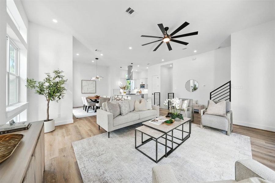 Spacious open-concept living area with high ceilings, wide-plank wood flooring, and abundant natural light. This modern layout seamlessly connects the living, dining, and kitchen spaces, featuring designer lighting, a sleek ceiling fan, and contemporary finishes—perfect for entertaining and everyday living. Spacious open-concept living area with high ceilings, wide-plank wood flooring, and abundant natural light. This modern layout seamlessly connects the living, dining, and kitchen spaces, featuring designer lighting, a sleek ceiling fan, and contemporary finishes—perfect for entertaining and everyday living.