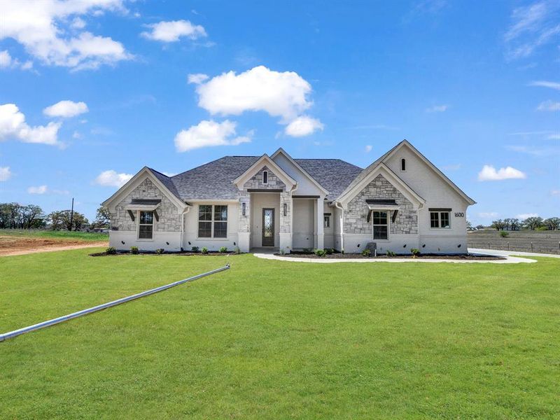 View of front of property with stone siding, a front lawn, and roof with shingles View of front of property with stone siding, a front lawn, and roof with shingles