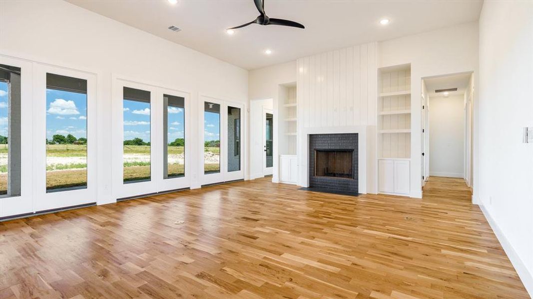 Unfurnished living room featuring built in features, plenty of natural light, light wood-type flooring, and a fireplace