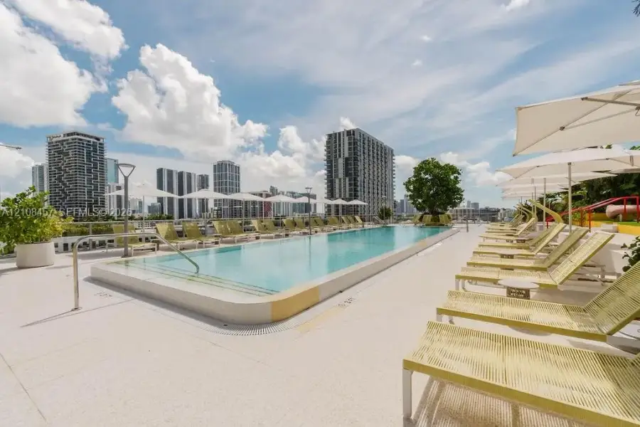 Rooftop swimming pool featuring a rectangular basin, light-colored hardscaping, integrated safety railing, and metal handrails Rooftop swimming pool featuring a rectangular basin, light-colored hardscaping, integrated safety railing, and metal handrails