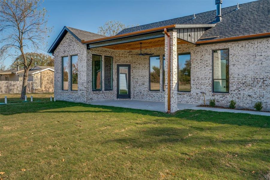 Back of house featuring brick siding, a patio area, ceiling fan, and roof with shingles Back of house featuring brick siding, a patio area, ceiling fan, and roof with shingles