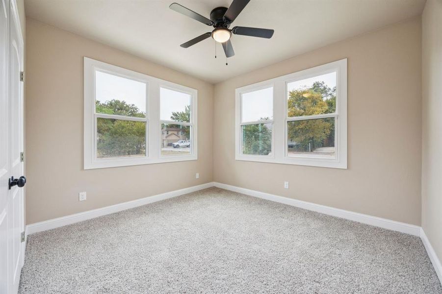 Carpeted bedroom with plenty of natural light and a ceiling fan Carpeted bedroom with plenty of natural light and a ceiling fan