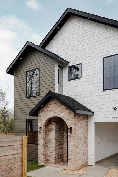 View of front facade featuring brick siding and a shingled roof