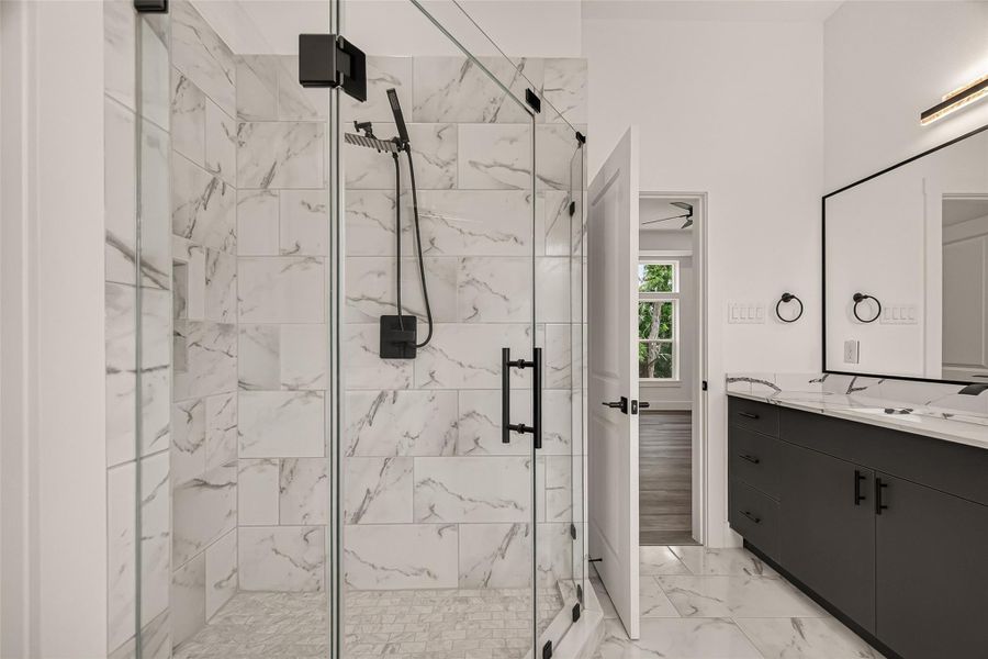 This bathroom features a modern glass-enclosed shower with elegant marble-style tiles, a sleek black vanity with a large mirror, and contemporary fixtures. The design is spacious and stylish, with high-quality finishes. This bathroom features a modern glass-enclosed shower with elegant marble-style tiles, a sleek black vanity with a large mirror, and contemporary fixtures. The design is spacious and stylish, with high-quality finishes.