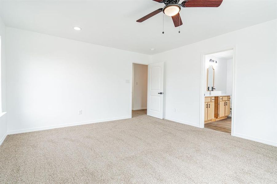 Unfurnished bedroom featuring connected bathroom, carpet, and ceiling fan