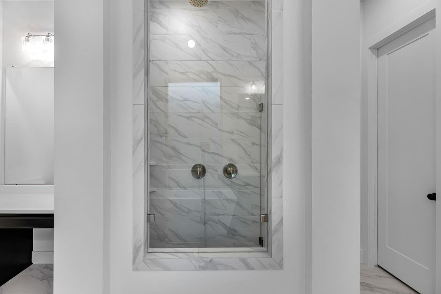 The primary shower has floor to ceiling tile and rain shower head. The primary shower has floor to ceiling tile and rain shower head.