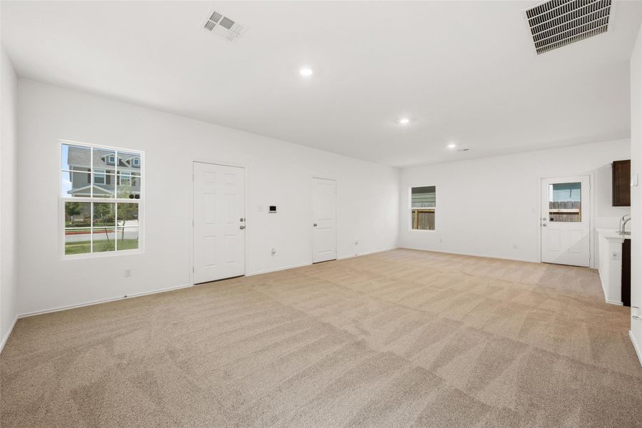 Unfurnished living room featuring light carpet and recessed lighting Unfurnished living room featuring light carpet and recessed lighting