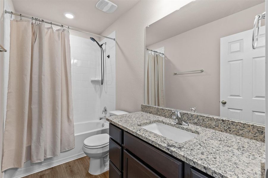 Full bathroom with shower / bath combo, dark wood-style floors, and vanity