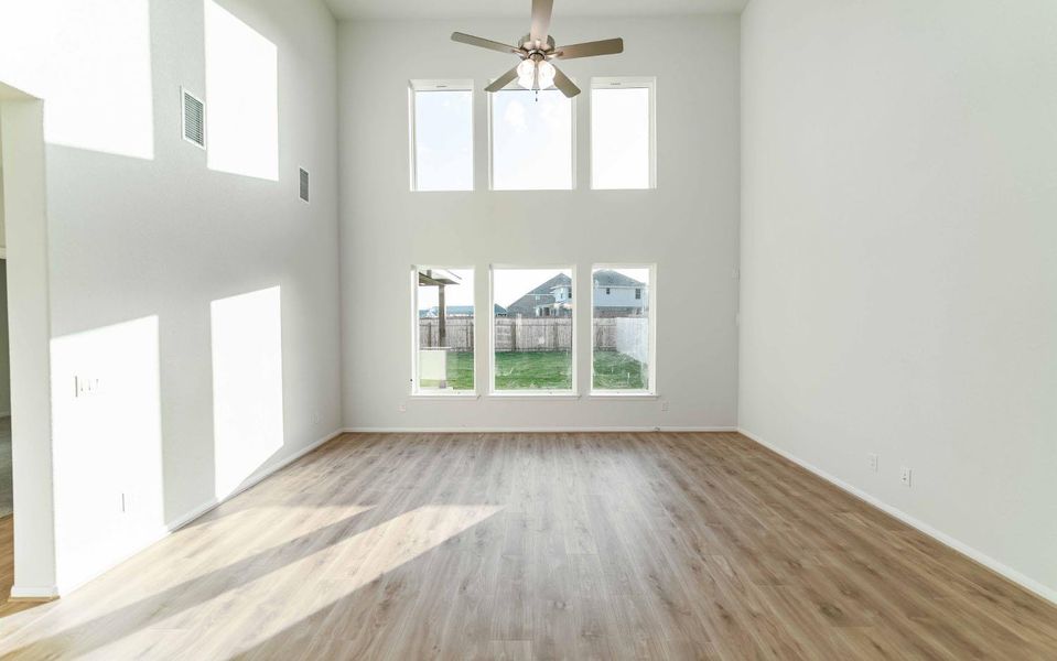 Unfurnished living room with a high ceiling, light wood-style floors, and ceiling fan
