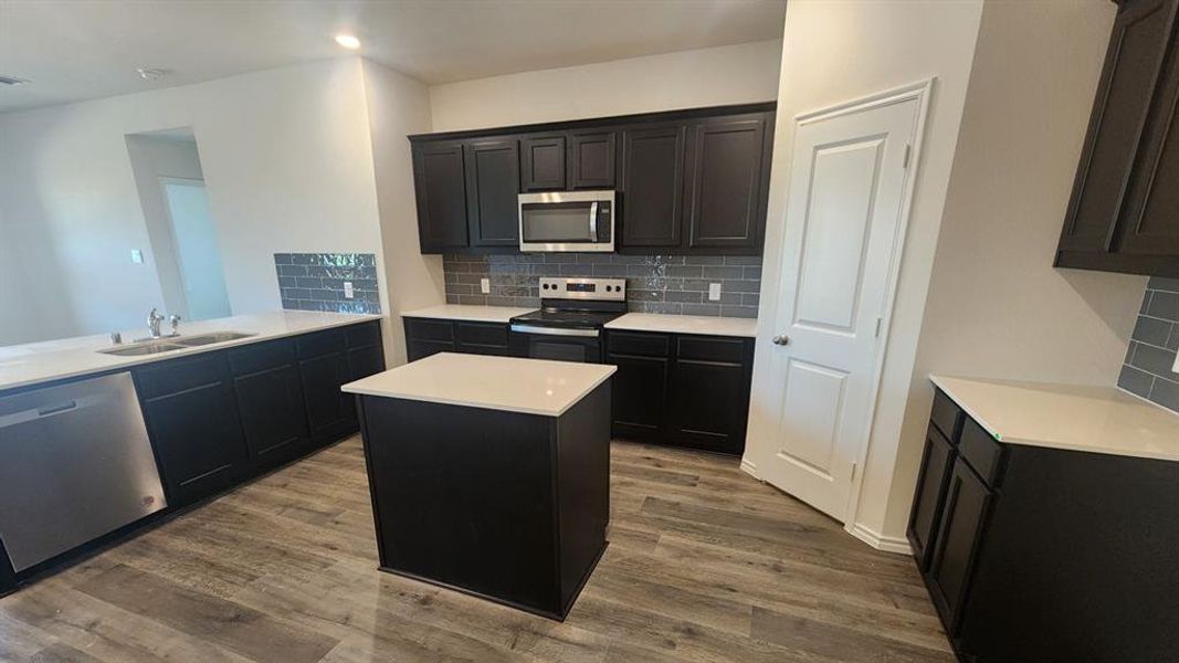 Modern kitchen featuring dark wood-finish cabinetry, light stone-finish countertops, and a subway tile backsplash Modern kitchen featuring dark wood-finish cabinetry, light stone-finish countertops, and a subway tile backsplash