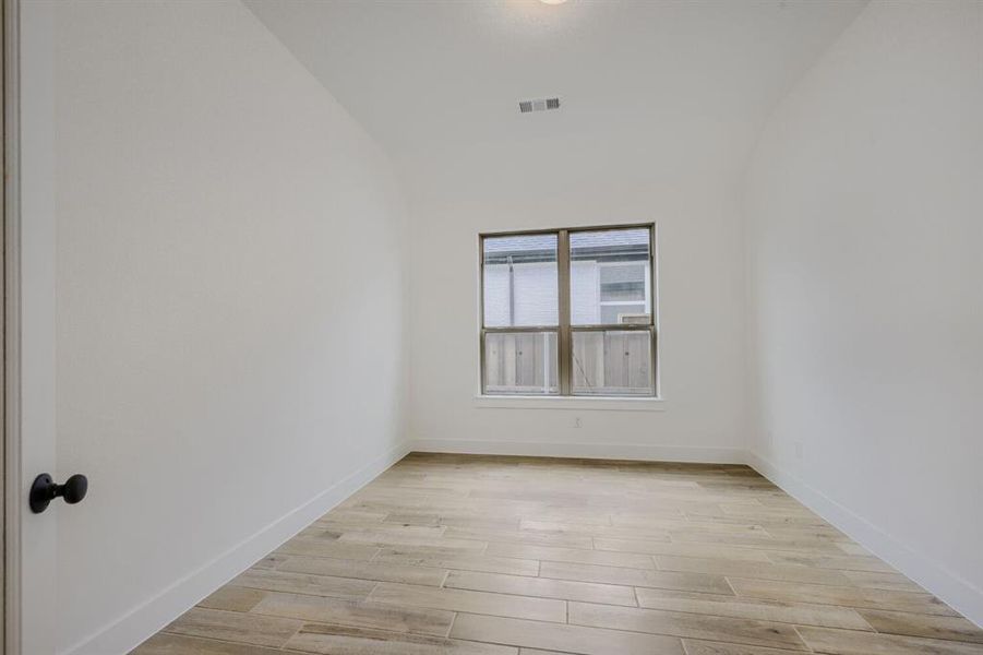 Room featuring wood-look tile flooring, white baseboards, and a single window with a dark frame