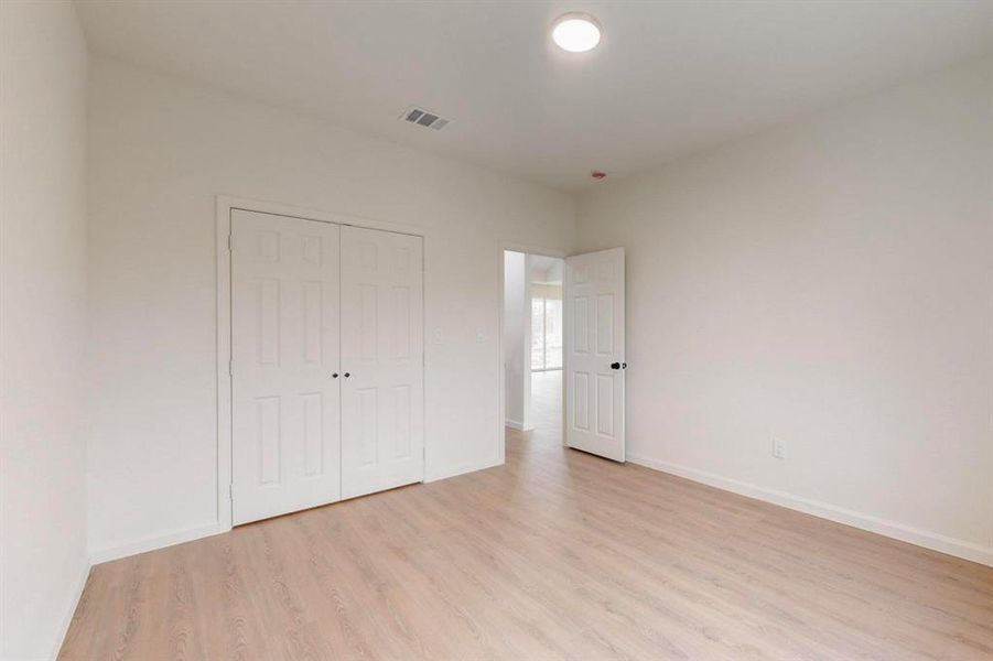 Unfurnished bedroom featuring baseboards, visible vents, a closet, and light wood-type flooring