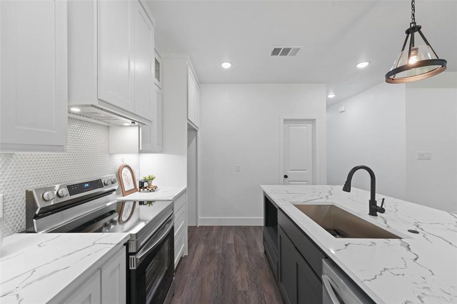 Modern kitchen featuring a large island with an undermount sink and matte black faucet Modern kitchen featuring a large island with an undermount sink and matte black faucet