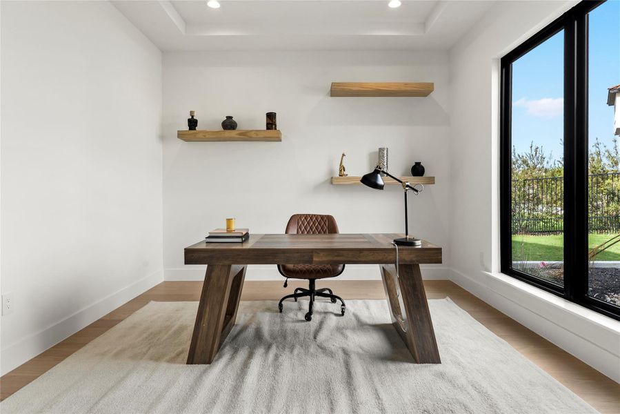 Office area featuring a tray ceiling, recessed lighting, and light wood finished floors Office area featuring a tray ceiling, recessed lighting, and light wood finished floors