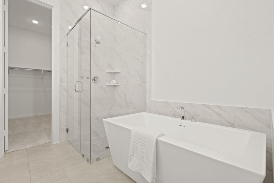 The spacious walk-in shower features warm, marble look tile extending from floor to ceiling, creating a spa-inspired feel while offering durability and easy maintenance.