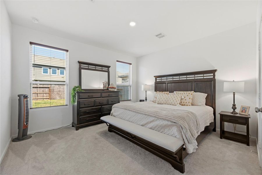 Private primary bedroom with large windows and neutral tones.