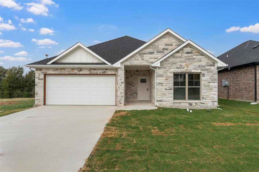 View of front of home featuring board and batten siding, driveway, a front lawn, an attached garage, and roof with shingles
