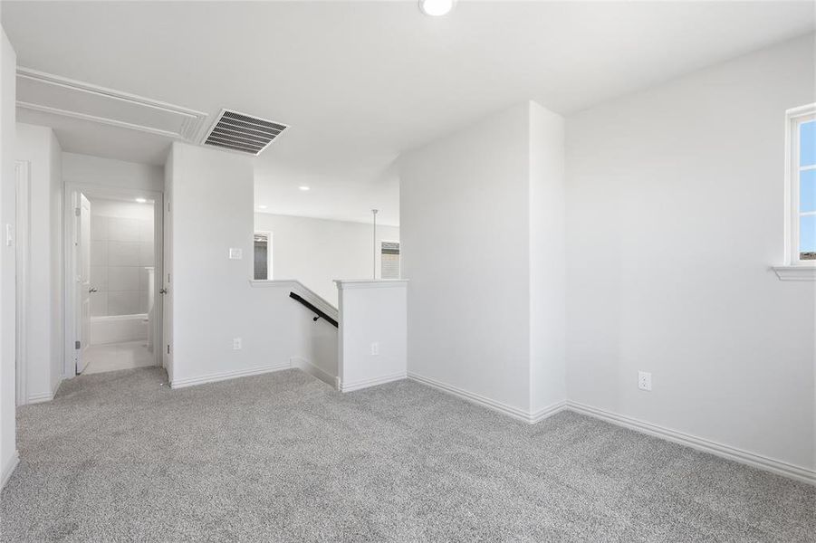 Carpeted room with a window providing natural illumination, complemented by an overhead light fixture