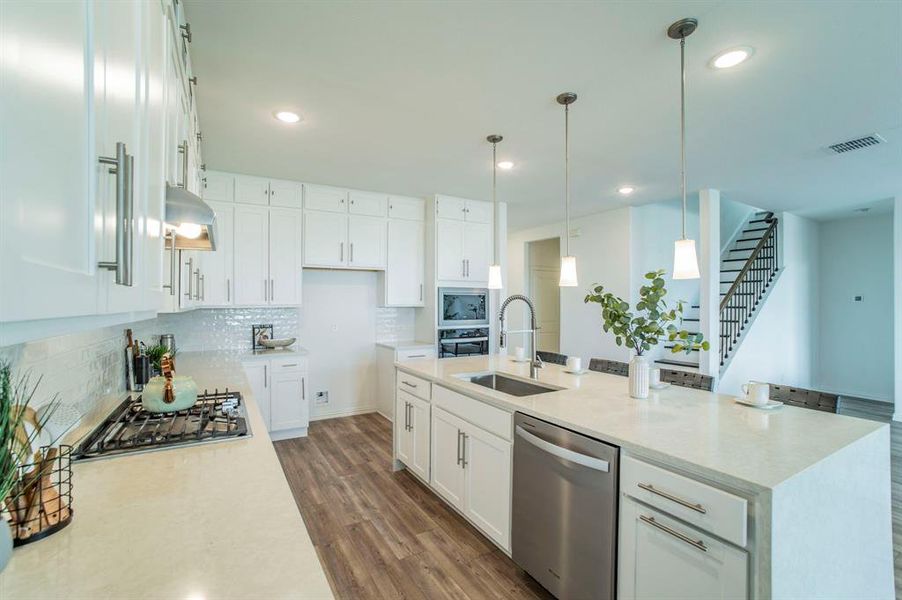 Kitchen featuring hanging light fixtures, stainless steel appliances, light stone countertops, white cabinetry, and decorative backsplash Kitchen featuring hanging light fixtures, stainless steel appliances, light stone countertops, white cabinetry, and decorative backsplash