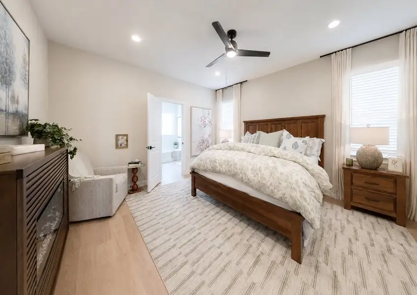 Staged bedroom in an LGI Homes model home at Canterra Creek, featuring a ceiling fan, recessed lighting, and wood-look flooring.