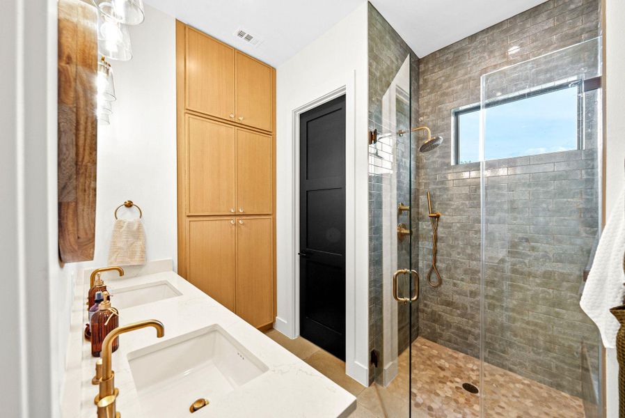 A glass-enclosed walk-in shower and a double vanity define this modern bathroom space.