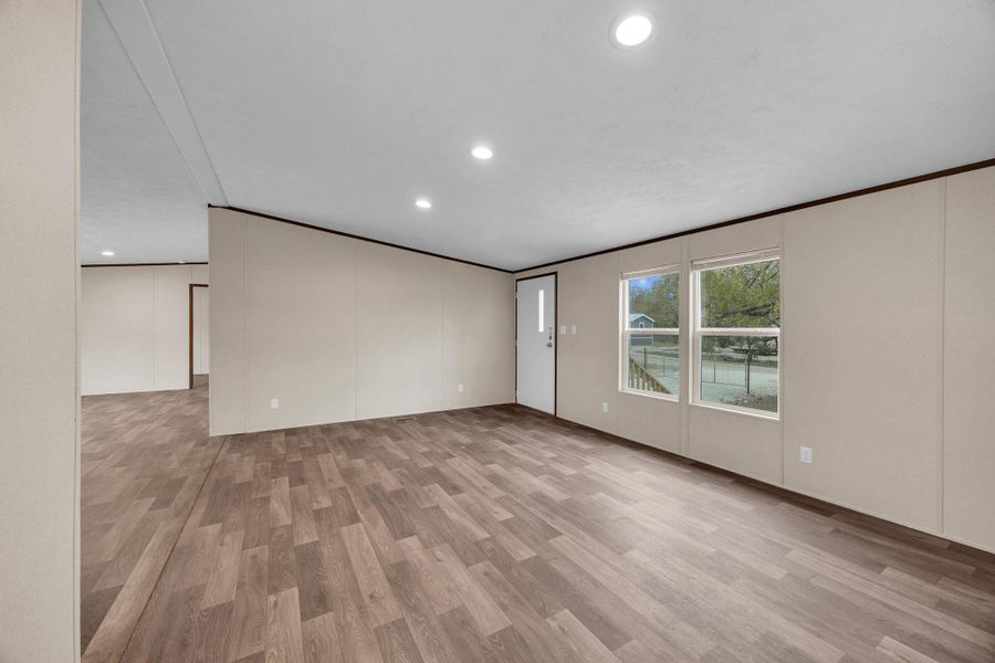Spare room with light wood-style floors, a decorative wall, ornamental molding, and recessed lighting