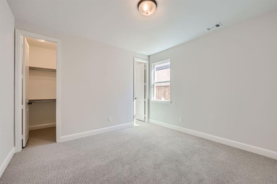 Unfurnished bedroom with carpet floors, a walk in closet, and a closet