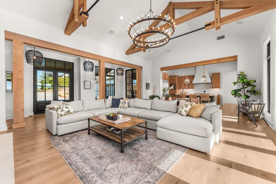 Living area featuring beamed ceiling, a chandelier, light wood-style floors, high vaulted ceiling, and french doors Living area featuring beamed ceiling, a chandelier, light wood-style floors, high vaulted ceiling, and french doors