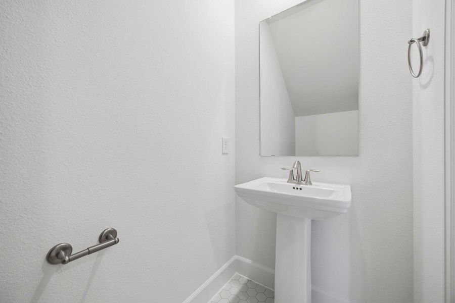 Nestled under the stairs, this powder room features a timeless pedestal sink, combining convenience and classic style.