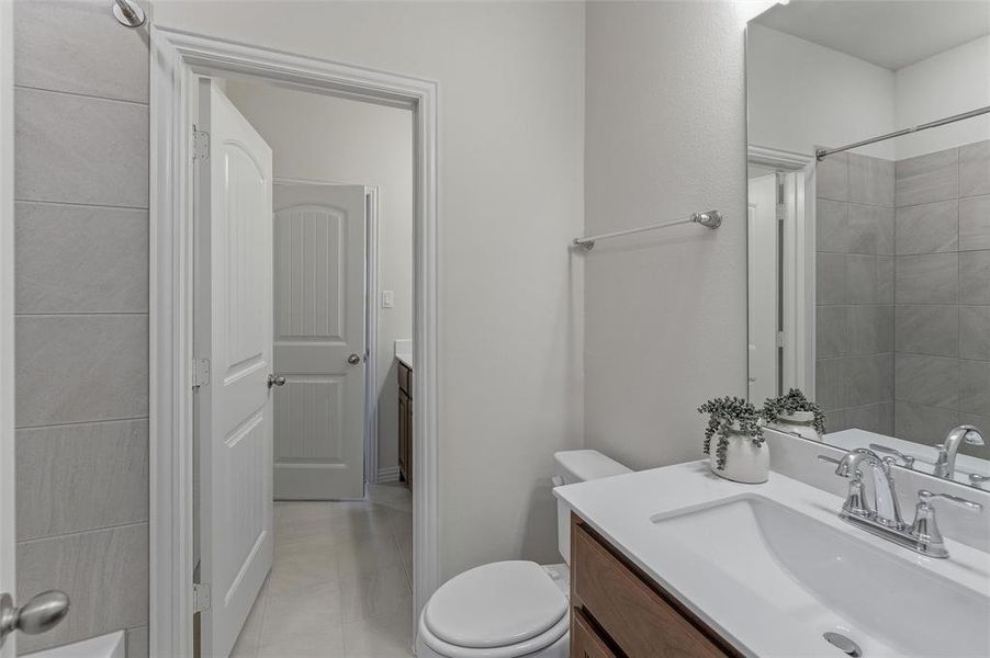 Bathroom featuring a single vanity with a white countertop and rectangular sink, polished chrome faucet, and wood-finish cabinetry