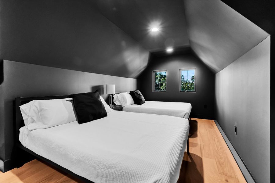 Bedroom with light wood-style flooring and lofted ceiling Bedroom with light wood-style flooring and lofted ceiling