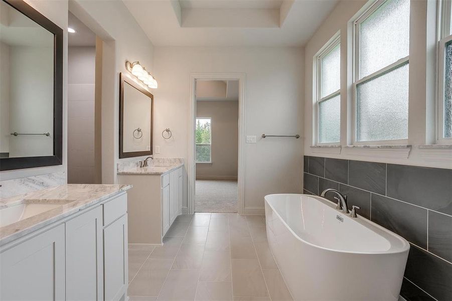 Bathroom with vanity, a wealth of natural light, a tub to relax in, and tile patterned floors