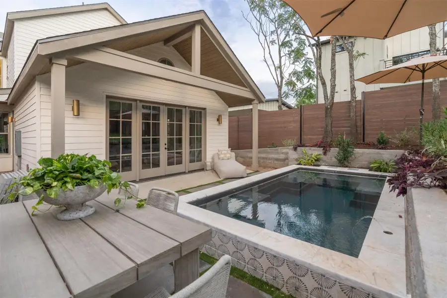 A covered back porch overlooks a private plunge pool set in a fenced backyard. A covered back porch overlooks a private plunge pool set in a fenced backyard.